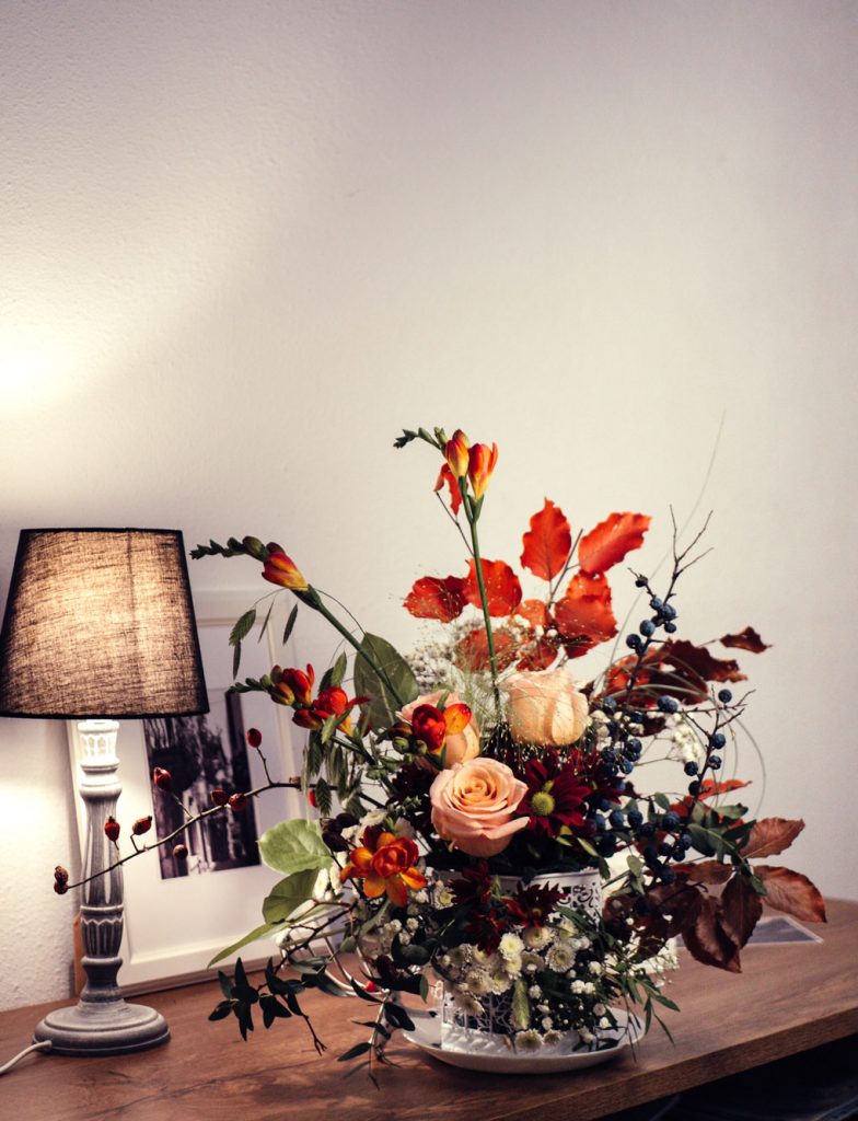 זר פרחים מונח על שולחן ומנורה