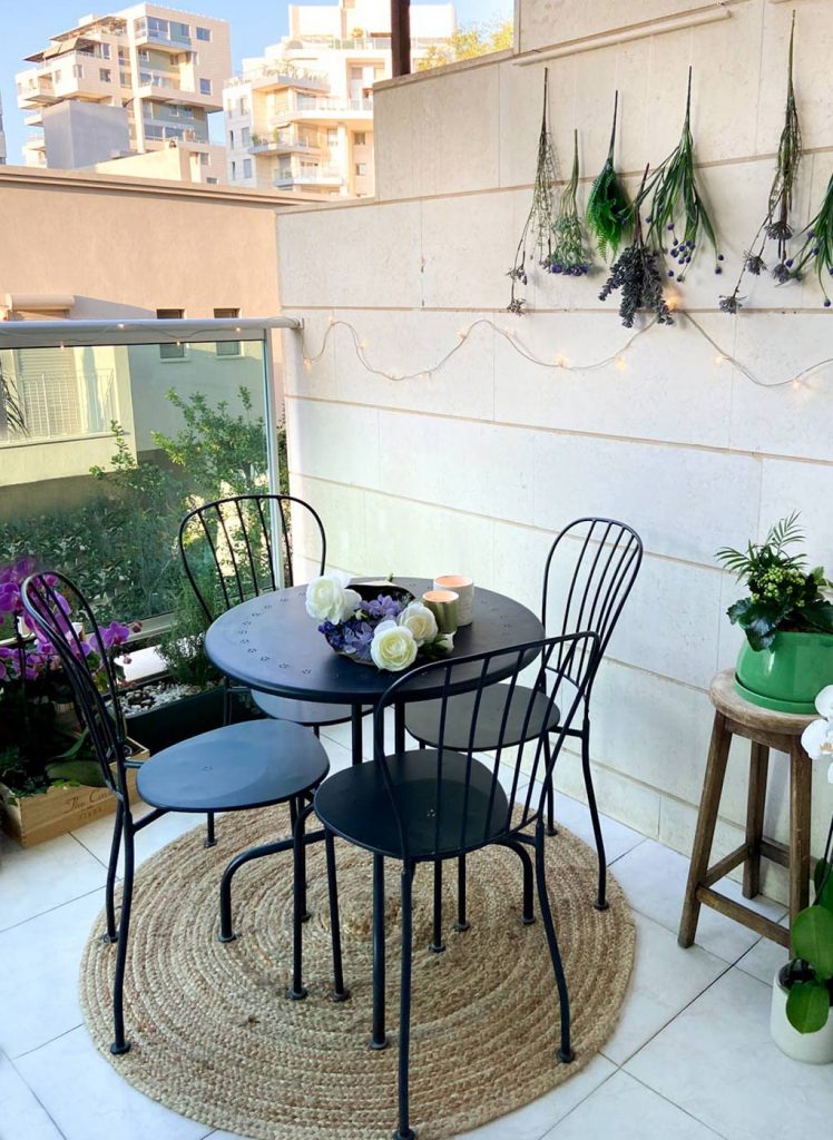 המרפסת לאחר השינוי, עם שולחן, כסאות, שטיח ועציצים